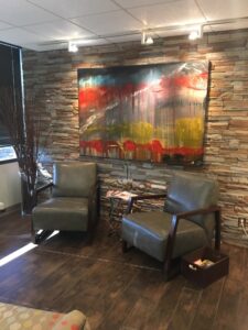 Cozy corner with two leather chairs and vibrant wall art in a rustic setting.