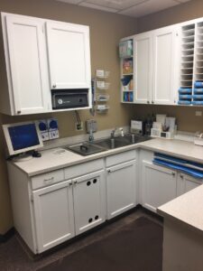Compact, organized medical workspace with clean white cabinets and equipment.