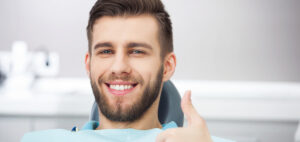 Bearded man smiling in dental chair thumbs up