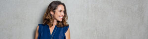 Smiling woman in blue blouse against wall
